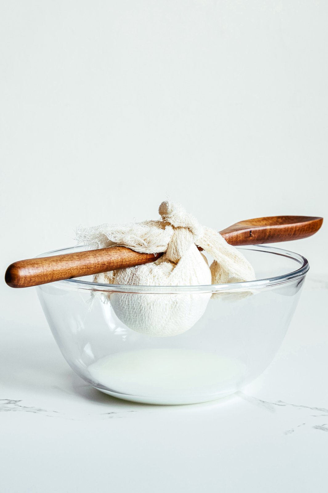 Greek yogurt tied over a spoon that rests across a bowl